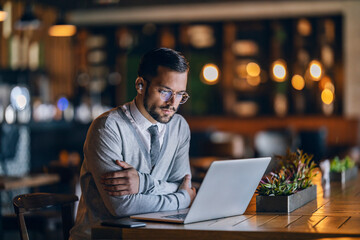 A stylish entrepreneur is sitting in cafeteria and working remotely.