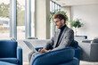 © Maria Vitkovska - Attractive smiling businessman wearing stylish suit using laptop computer working online planning startup in modern office. Portrait of successful freelancer copywriter typing sitting at workplace