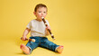 © Андрей Журавлев - Toddler baby plays the flute, a child with a wind musical instrument on a studio yellow background. Happy child musician playing block flute, copy space. Kid aged one year and four months