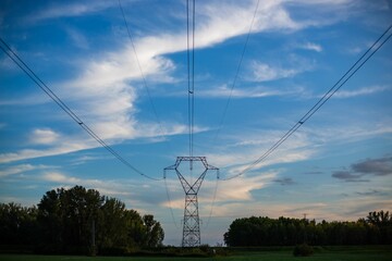 Wall Mural - Transmission tower in the green field at sunset