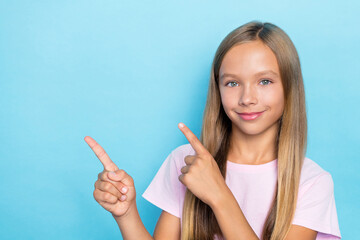 Poster - Portrait of good mood small girl straight hairstyle wear pink t-shirt fingers indicating empty space isolated on blue color background