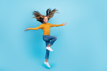 Canvas Print - Full size photo of good mood girl fluttering hair dressed yellow turtleneck denim pants palms up isolated on blue color background