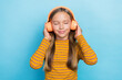 Photo of peaceful cute girl closed eyed hands touch headphones listen new song isolated on blue color background