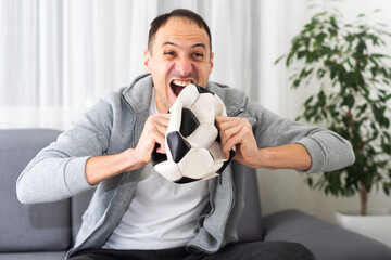 Soccer Fan. Emotional Guy Shouting Celebrating Victory Of Team Holding Ball Posing On Studio Background.