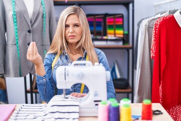 Sticker - Blonde woman dressmaker designer using sew machine doing italian gesture with hand and fingers confident expression