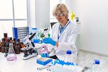 Wall Mural - Young blond man scientist smiling confident weighing test tube at laboratory