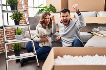 Sticker - Young hispanic couple sitting on the floor at new home with log annoyed and frustrated shouting with anger, yelling crazy with anger and hand raised