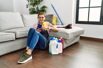 Sticker - Young woman cleaner using smartphone sitting on floor at home