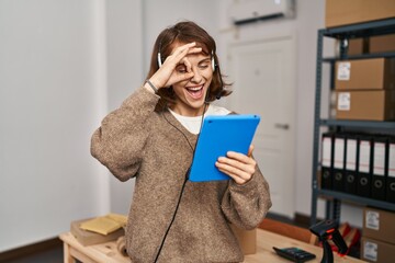 Sticker - Young beautiful woman working at small business ecommerce smiling happy doing ok sign with hand on eye looking through fingers