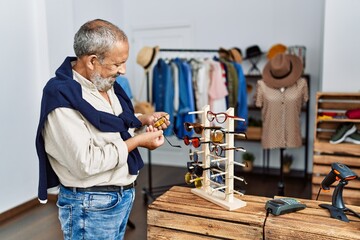 Poster - Senior grey-haired man smiling confident holding glasses at clothing store