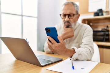 Canvas Print - Senior grey-haired man using smartphone working at office