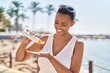 African american woman smiling confident applying sunscreen lotion at seaside