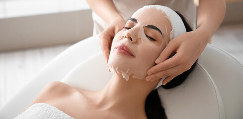 Canvas Print - Cosmetologist applying mask onto woman's face in beauty salon