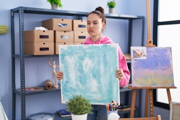 Canvas Print - Young hispanic girl holding canvas depressed and worry for distress, crying angry and afraid. sad expression.