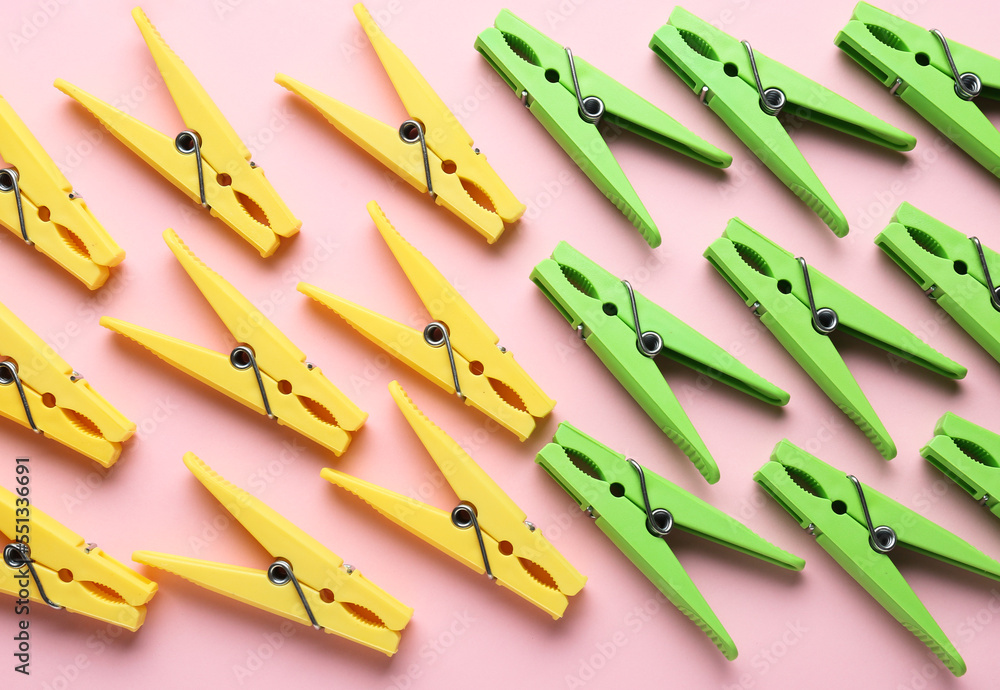 Different plastic clothespins on pink background, closeup
