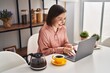 © Krakenimages.com - Middle age woman having breakfast using laptop sitting on table at home