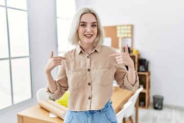 Wall Mural - Young beautiful caucasian woman at construction office looking confident with smile on face, pointing oneself with fingers proud and happy.