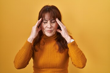 Sticker - Middle age hispanic woman standing over yellow background with hand on head, headache because stress. suffering migraine.