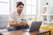 © Krakenimages.com - Young hispanic man using laptop and smartphone sitting on sofa at home