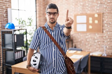 Canvas Print - Hispanic man with long hair working at the office holding bike helmet pointing with finger up and angry expression, showing no gesture