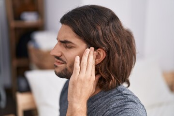 Sticker - Young hispanic man suffering for headache sitting on bed at bedroom