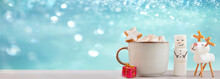 Christmas Mug With Hot Chocolate And Marshmallows. XMas Handmade Marshmallow Snowman And Christmas Deer. Christmas Festive Banner With Snowly Blue Glittering Background, Copy Space For Text.