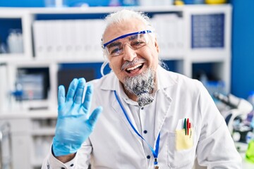 Sticker - Middle age man with grey hair working at scientist laboratory looking positive and happy standing and smiling with a confident smile showing teeth