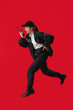 © Pixel-Shot - Female police officer with radio transmitter jumping on red background