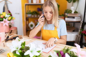 Poster - Young blonde woman florist talking on smartphone reading book at flower shop