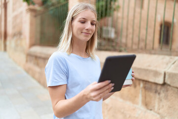 Poster - Young blonde woman using touchpad drinking coffee at street