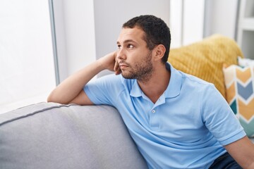 Sticker - Young man sitting on sofa with relaxed expression at home