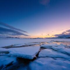 Wall Mural - north, norway. winter landscape during sunset. bright sky. ice and snow on the shore. reflections on