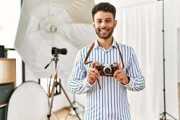 Canvas Print - Young arab photographer man smiling happy using vintage camera at photo studio.