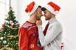 © Krakenimages.com - Two hispanic men couple hugging each other standing by christmas tree at home
