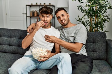 Sticker - Two hispanic men couple watching movie sitting on sofa at home