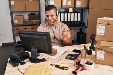 Canvas Print - Hispanic young man working at small business ecommerce smiling happy pointing with hand and finger to the side