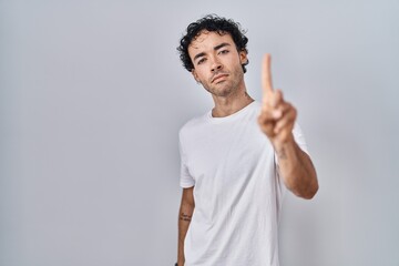 Wall Mural - Hispanic man standing over isolated background pointing with finger up and angry expression, showing no gesture