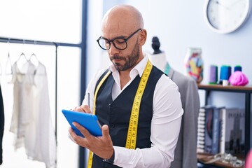 Canvas Print - Young bald man tailor using touchpad at tailor shop