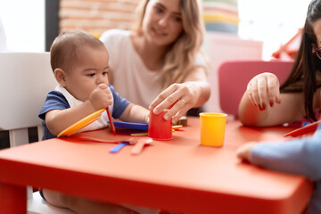 Wall Mural - Teacher and preschool student learning to eat sitting on table at kindergarten