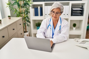 Poster - Middle age woman wearing doctor uniform working at clinic