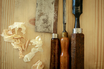 Traditional carpenter's tools on light wooden table; a saw and two chisels