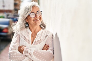 Wall Mural - Middle age woman smiling confident standing with arms crossed gesture at street