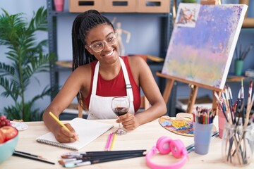 Sticker - African american woman artist drinking wine drawing on notebook at art studio