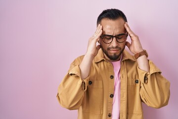 Canvas Print - Young hispanic man standing over pink background with hand on head for pain in head because stress. suffering migraine.