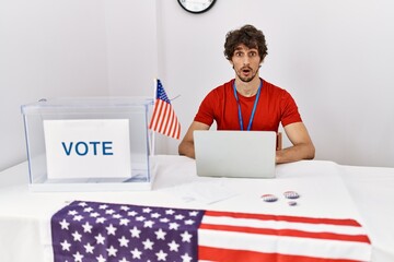 Canvas Print - Young hispanic man at political election sitting by ballot afraid and shocked with surprise expression, fear and excited face.