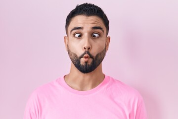 Sticker - Hispanic young man standing over pink background making fish face with lips, crazy and comical gesture. funny expression.