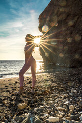 Wall Mural - Girl gymnast is training on the beach by the sea sunset. Does twine. Photo series.