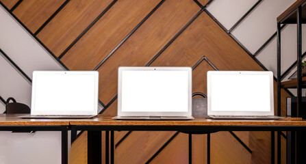 Multiple laptop screen mockups on wood desk in modern office. Multi display, monitor mock up of computer displays