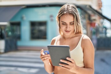 Poster - Young blonde woman using touchpad and credit card at street