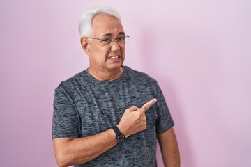 Canvas Print - Middle age man with grey hair standing over pink background pointing aside worried and nervous with forefinger, concerned and surprised expression